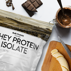 Bulk Protein Canada Chocolate Banana whey protein isolate on a table with cut banana et piece of chocolate