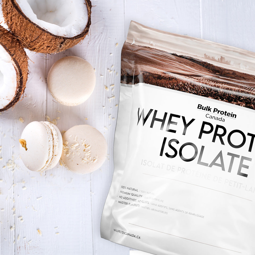 Bulk Protein Canada Coconut Island whey protein isolate on a table with coconut piece and macaron